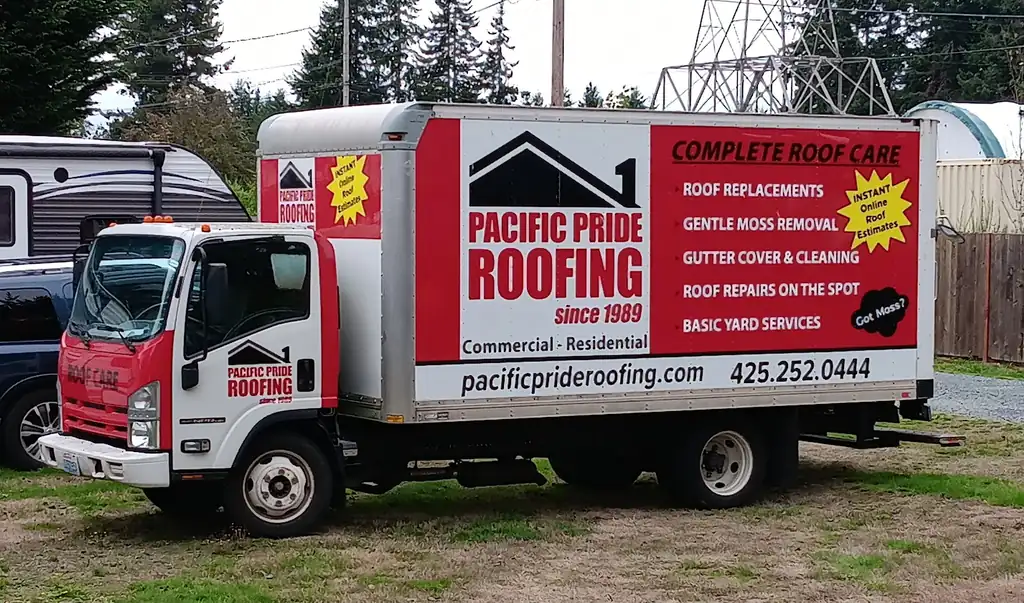 The Pacific Pride Roofing box truck in its red and white livery, listing roof replacements, gentle moss removal, gutter cover and cleaning and roof repairs