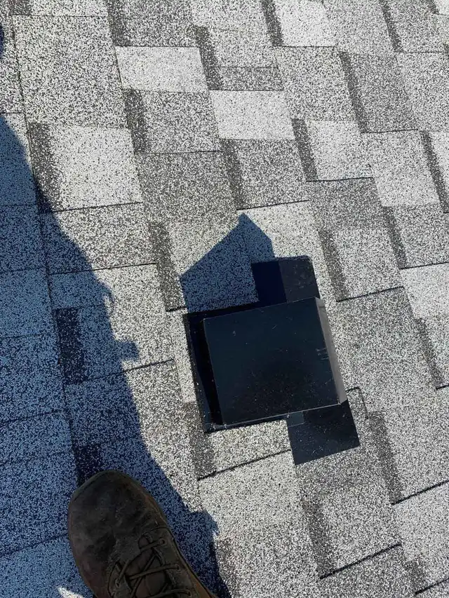 Close view of a roof vent seated in grey shingles during an inspection